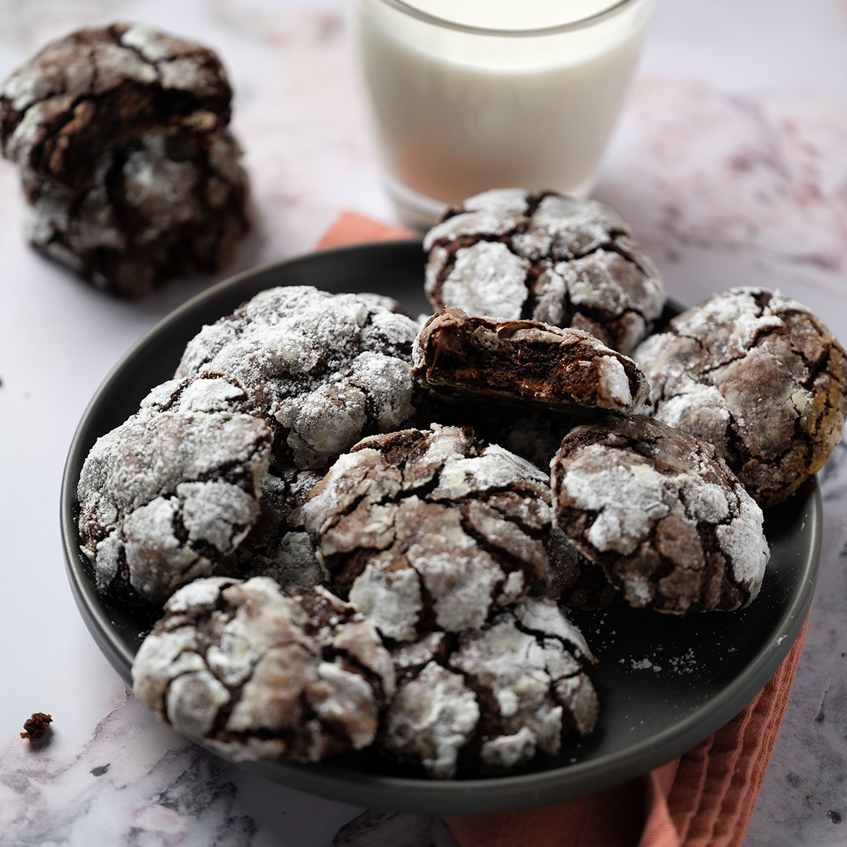A plate full of crinkle cookies next to a glass of milk.