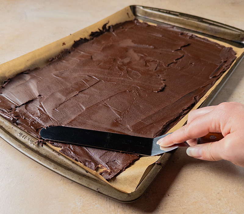 Spreading brownie brittle batter into a thin layer on a baking sheet.