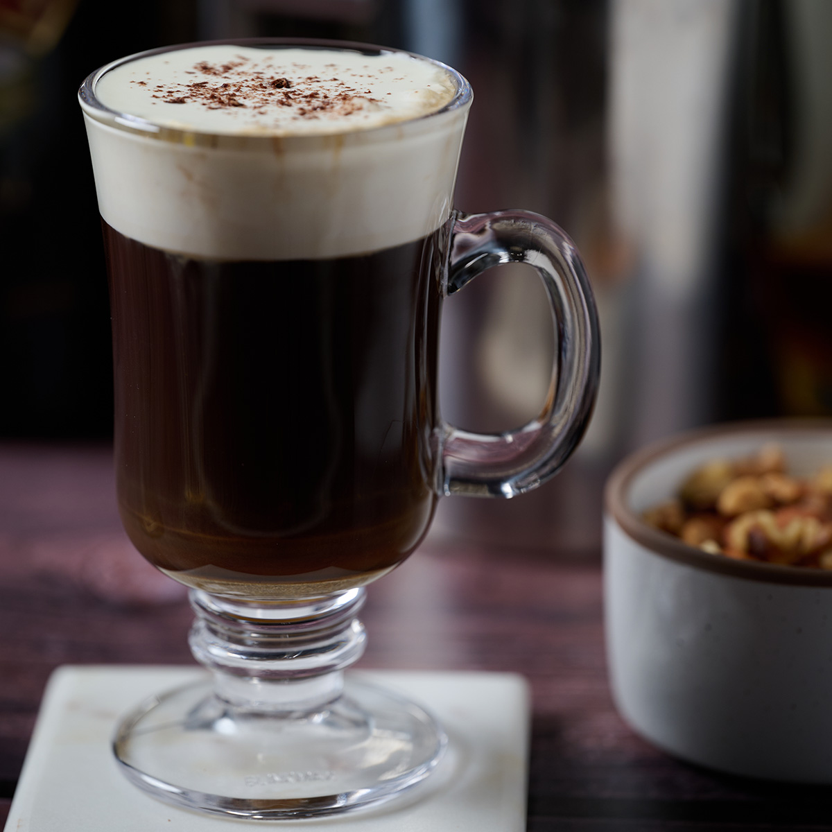 Chocolate Irish coffee at the bar next to a bowl of mixed nuts.
