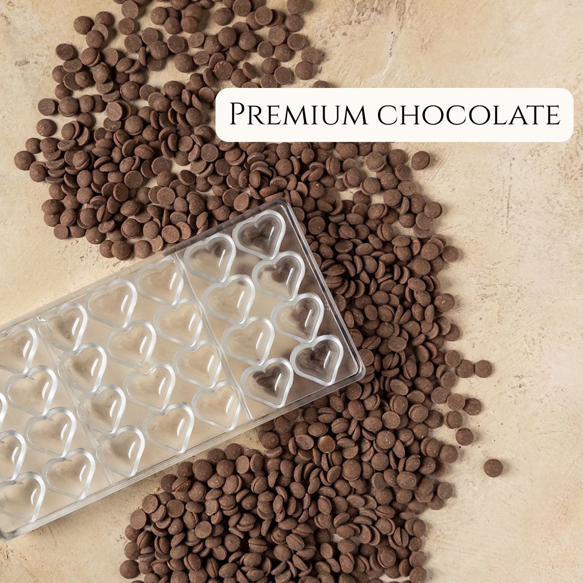 Premium chocolate pistoles and a chocolate mold with heart-shaped cavities.