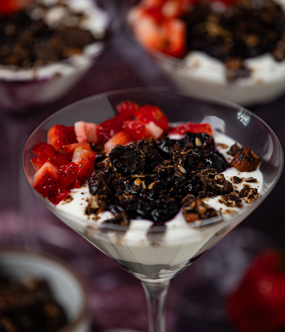 Chocolate granola on top of a blueberry yogurt parfait with diced strawberries.