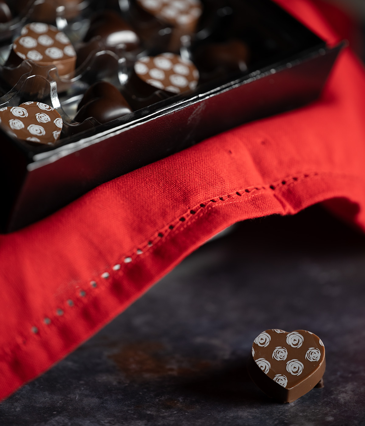 A milk chocolate heart outside a box of chocolates.