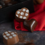 Two solid chocolate hearts on red fabric.