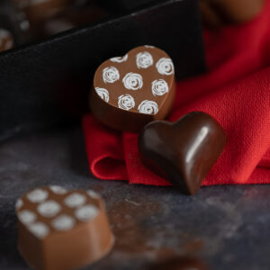 Two solid chocolate hearts on red fabric.