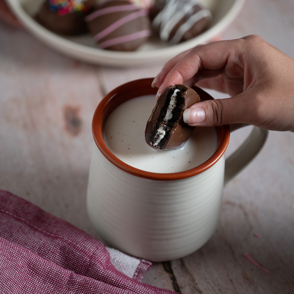 Dunking a chocolate-covered Oreo in milk.