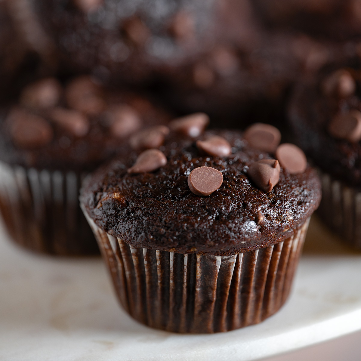 A macro shot of a double chocolate chip muffin on a cake plate.