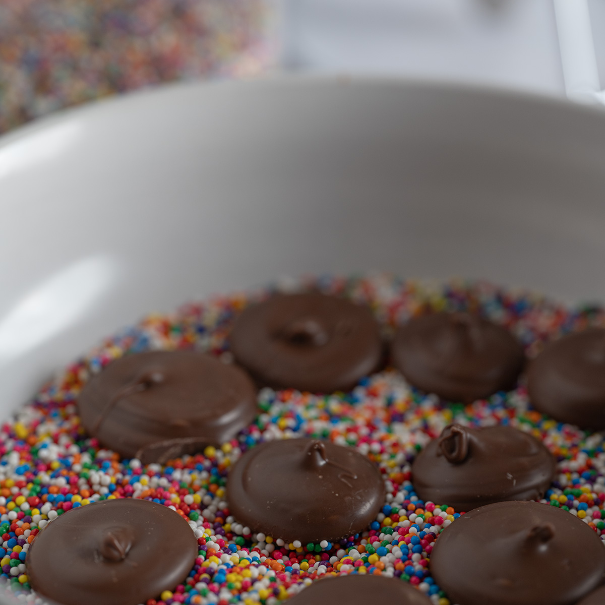 Nonpareils setting on a bed of rainbow sprinkles.