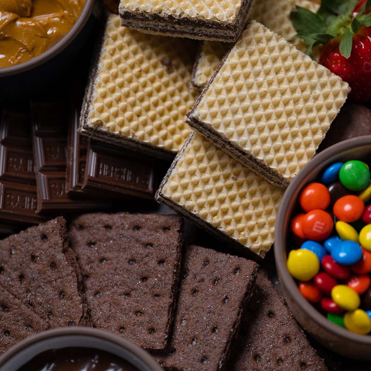 M&Ms and crackers and cookies on a s'mores charcuterie board.