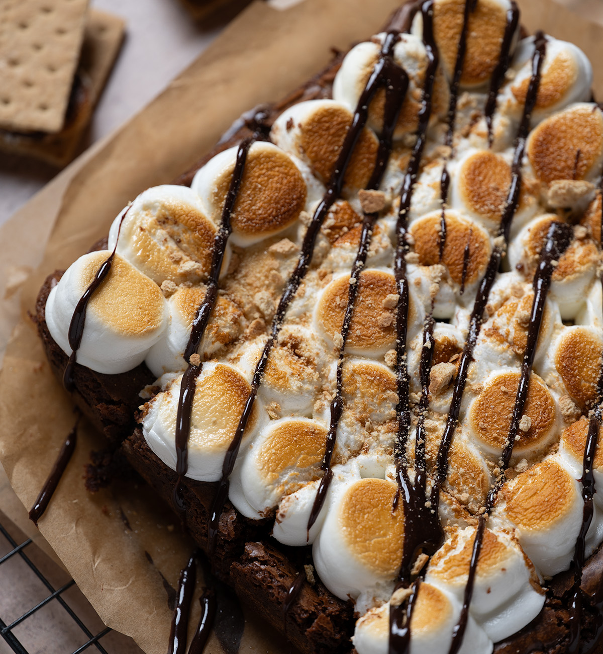 A tray of s'mores brownies with chocolate drizzle and graham cracker crumbs.