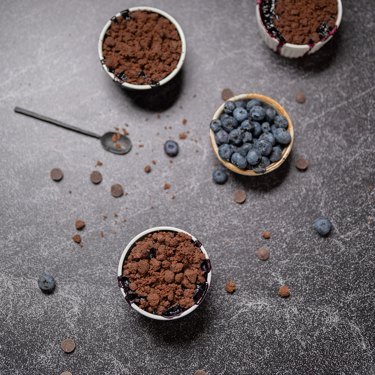 Two ramekins of dark chocolate blueberry crisp and one ramekin of white chocolate blueberry crisp.