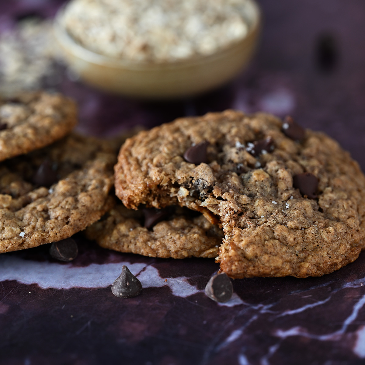 A bite taken out of a chocolate chip oatmeal raisin cookie.