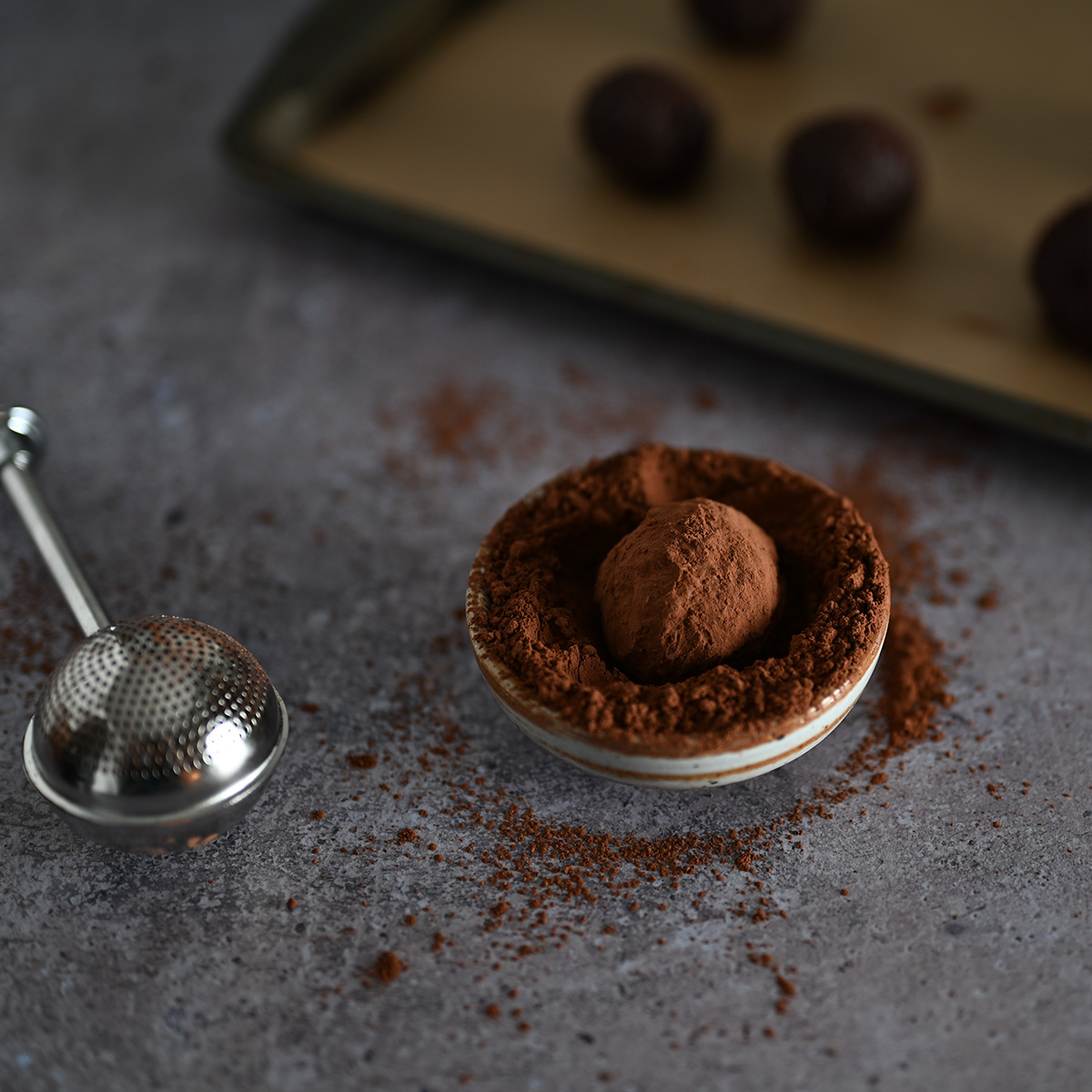 Rolling a classic dark chocolate ganache truffle in cocoa powder.
